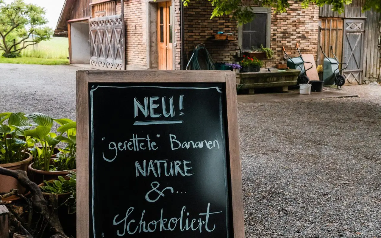 Schiefertafel vor dem Hofladen mit der Aufschrift: Gerettete Bananen nature & schokoliert